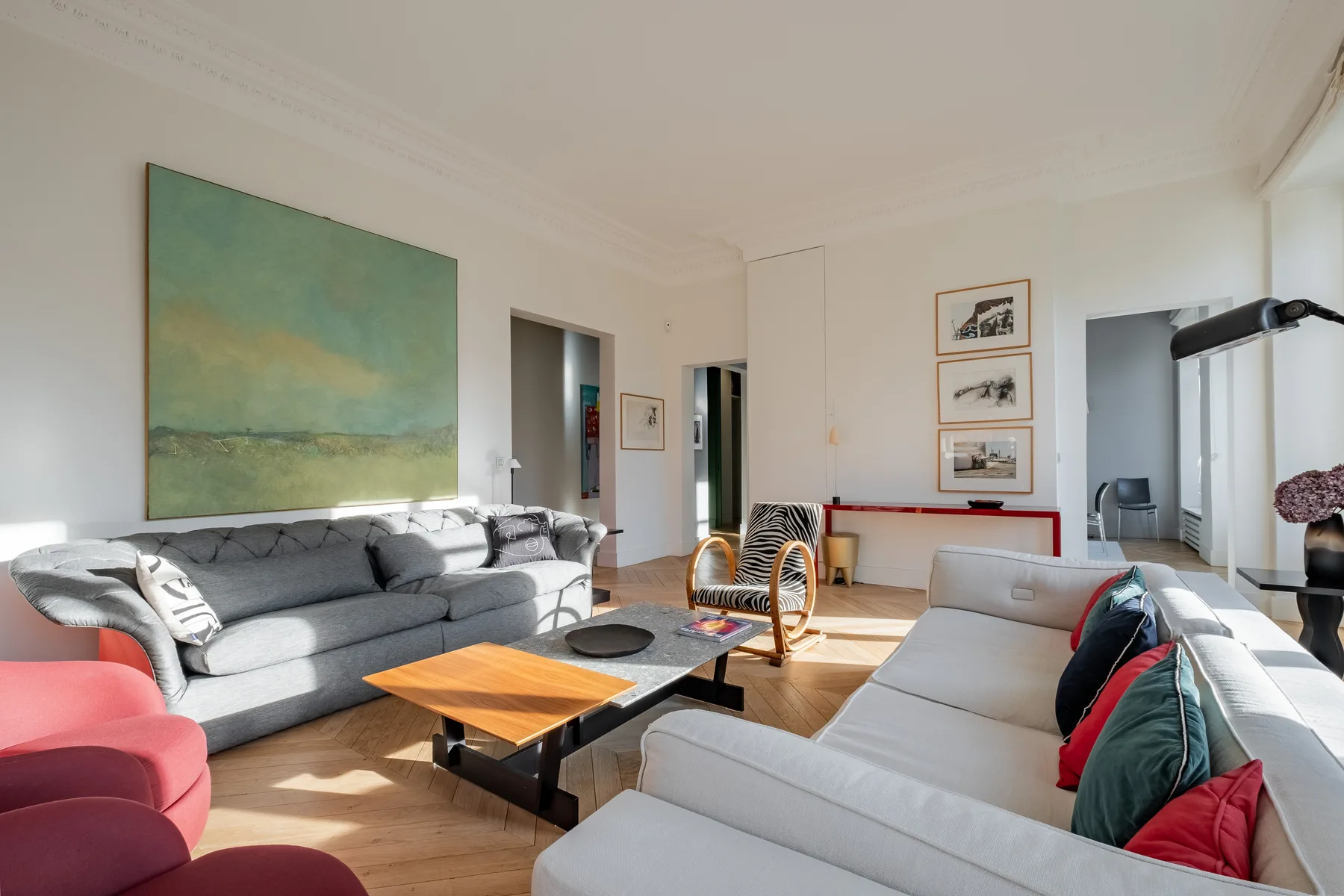 A bright living room with gray seating, a large painting, and a low coffee table.