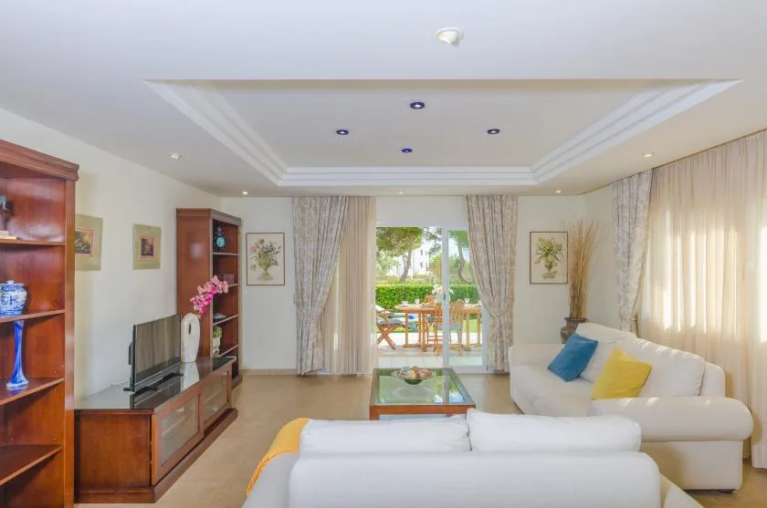A bright living room with seating, a television, and glass doors opening to a patio.