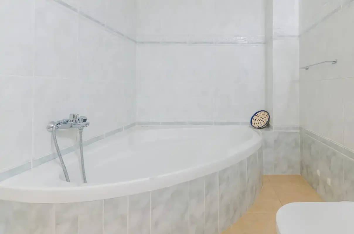 A bathroom with a large bathtub and wall-mounted shower fixture.