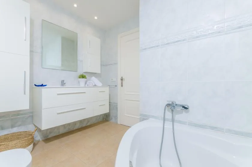 A bright bathroom with a vanity, mirror, and bathtub.
