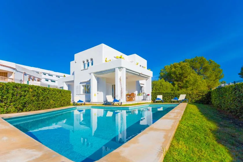A modern white house stands beside a swimming pool and green lawn.