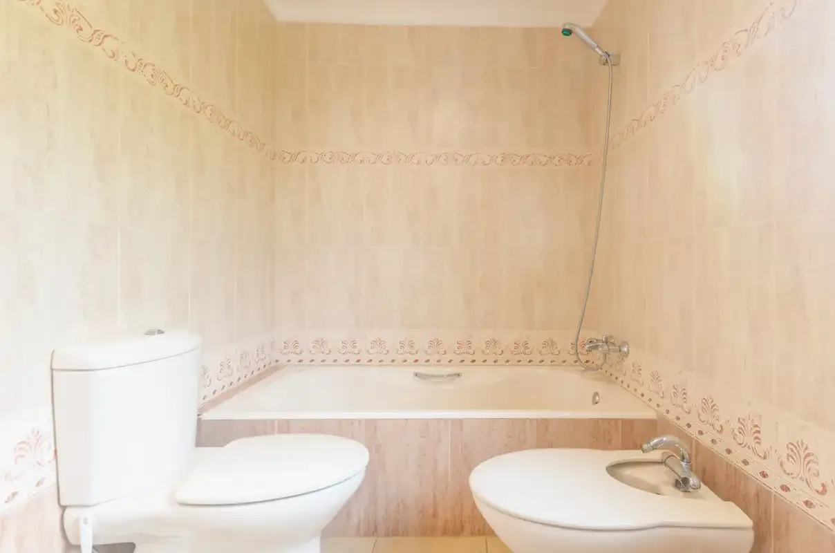 A bathroom with a bathtub, toilet, and bidet.