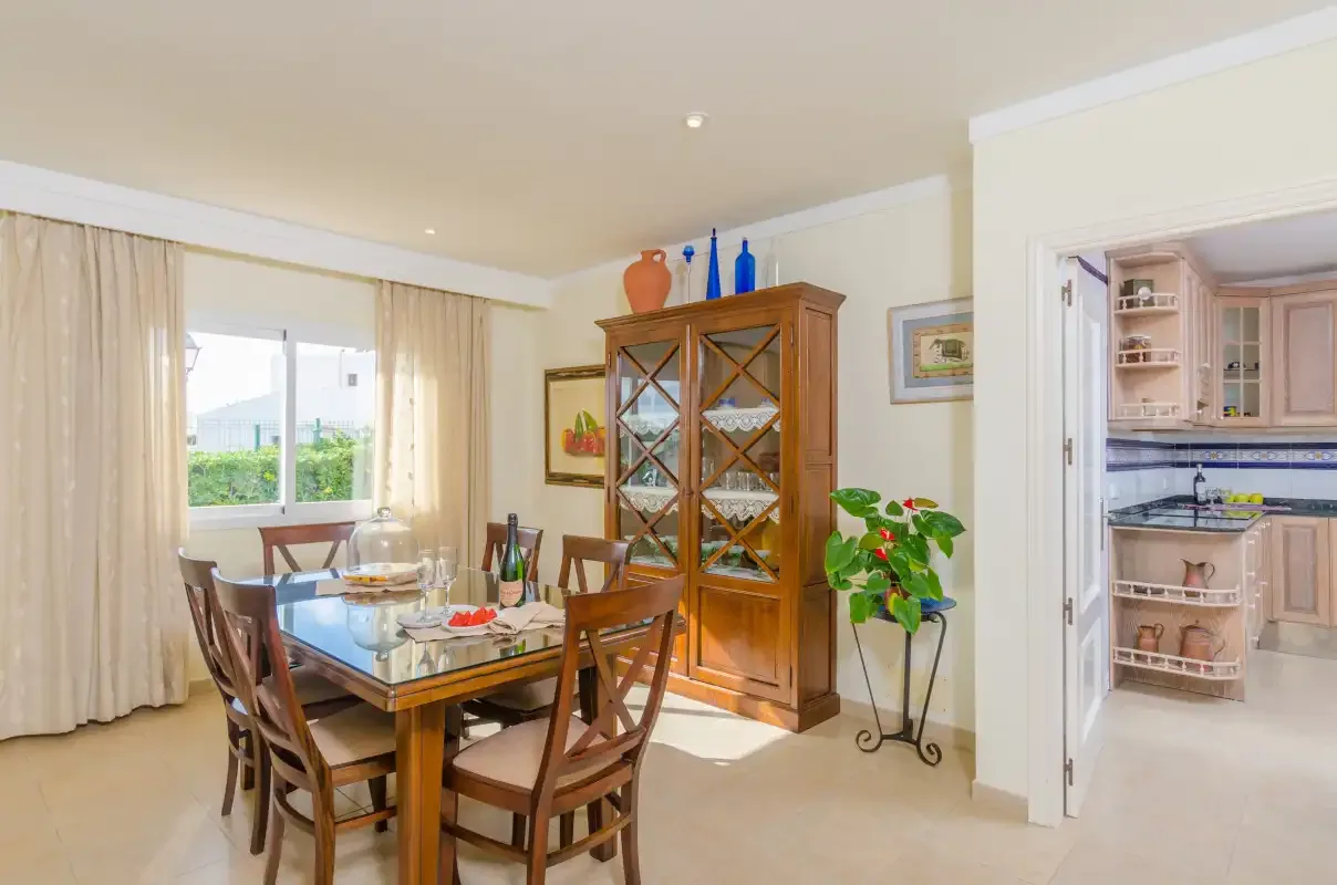 A dining area with a wooden table and chairs beside a glass-front cabinet.