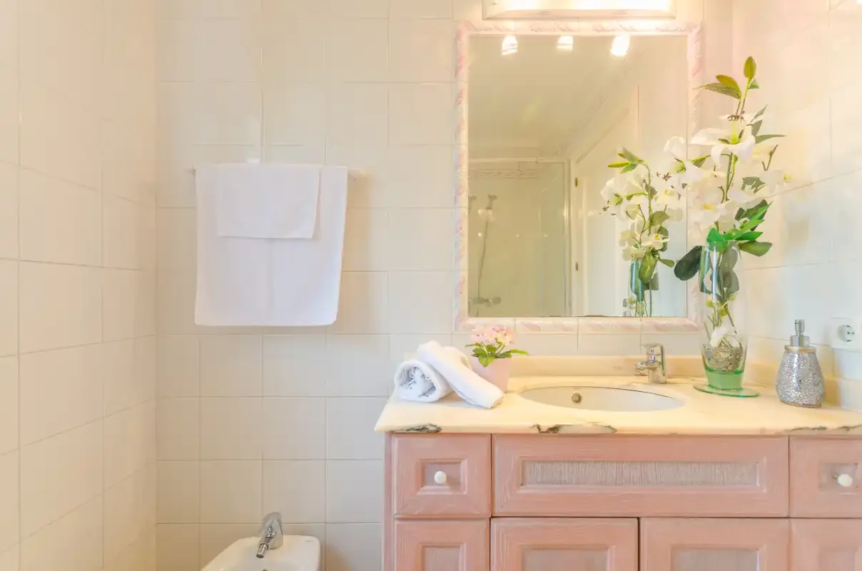 A tiled bathroom with a sink, mirror, and folded towels.