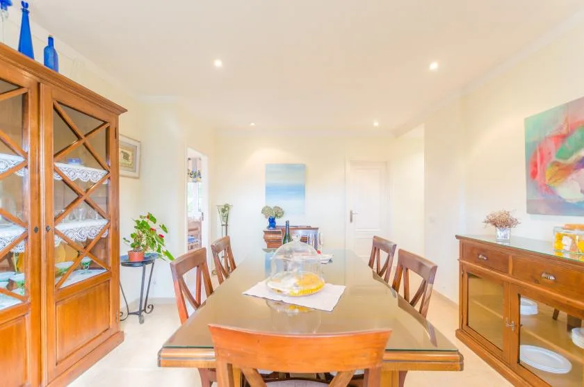 A bright dining room with a wooden table and chairs, surrounded by wooden cabinets.