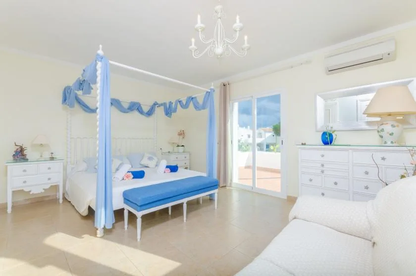 A bright bedroom with blue canopy beds and glass doors opening to a balcony.