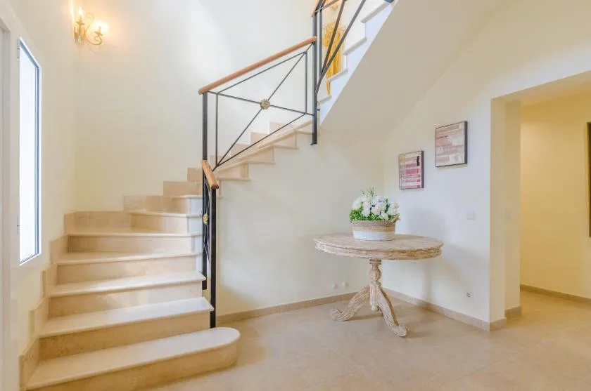 A bright stairwell with a curved staircase and a small round table.