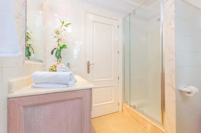 A bright bathroom with a vanity, folded towels, and a glass shower.