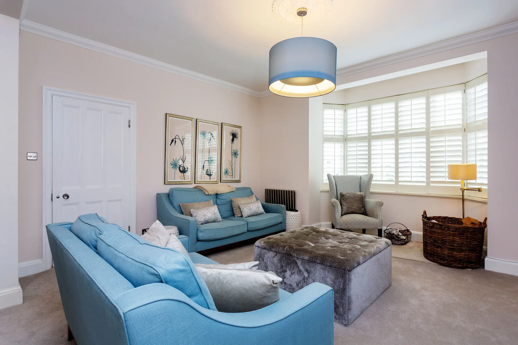 A bright living room with blue seating and a large bay window.