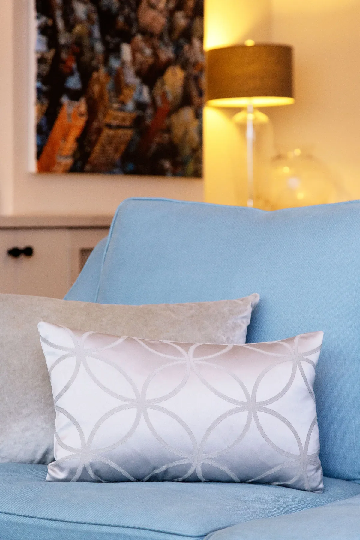 A blue seating area with patterned cushions and a table lamp.