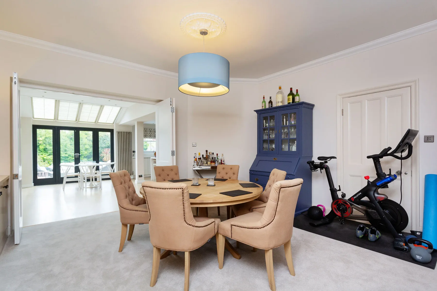 A dining area with a round table and exercise equipment beside it.