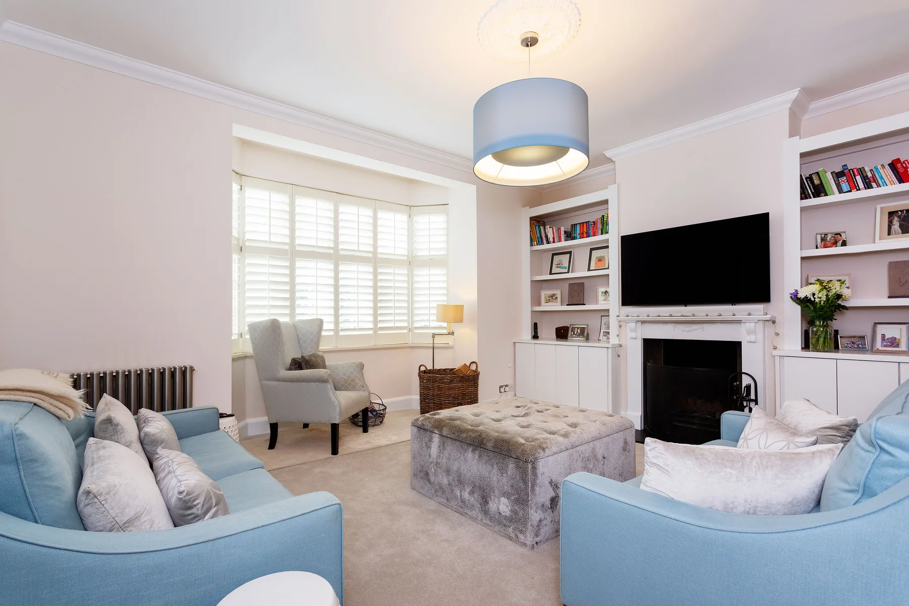 A bright living room with blue seating, a fireplace, and built-in shelves.
