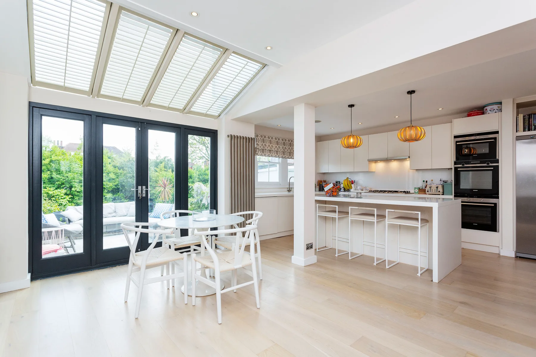 A bright open-plan kitchen and dining area with a white island and table.