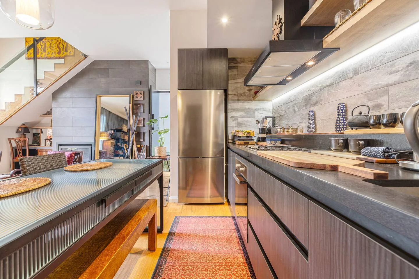 Una cocina con una encimera larga, un refrigerador de acero inoxidable y una mesa de comedor.
