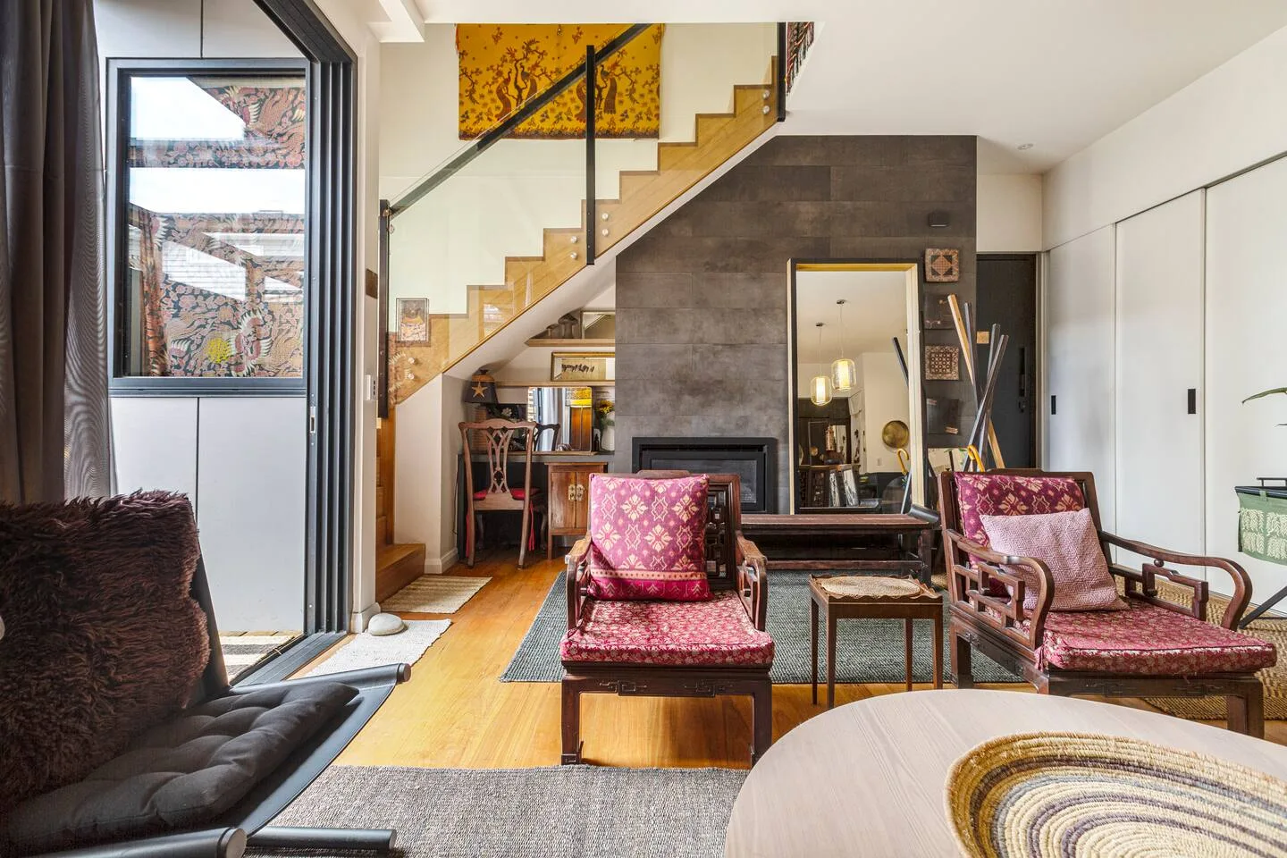 Una sala de estar con asientos estampados, una chimenea y una escalera.