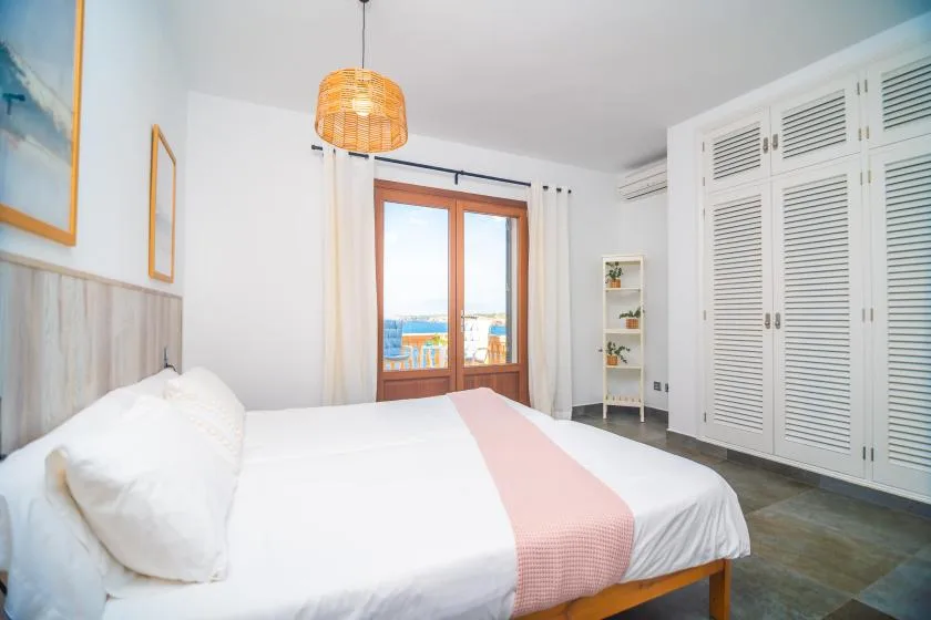 A bedroom with a neatly made bed and glass doors opening onto a balcony.