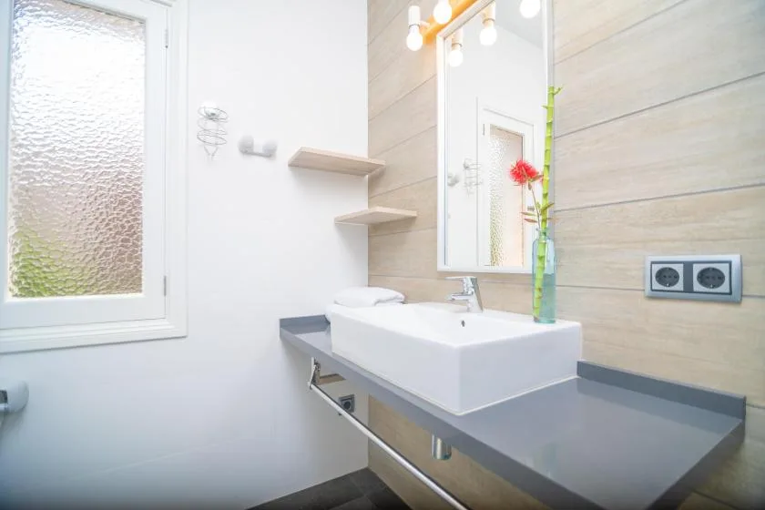 A bright bathroom with a white vessel sink beneath a wall mirror.