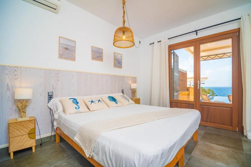 A bedroom with a neatly made bed and glass doors opening onto a balcony.