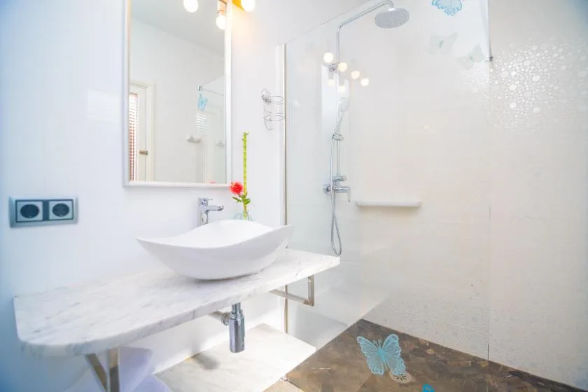 A bright bathroom with a vessel sink and a glass shower.
