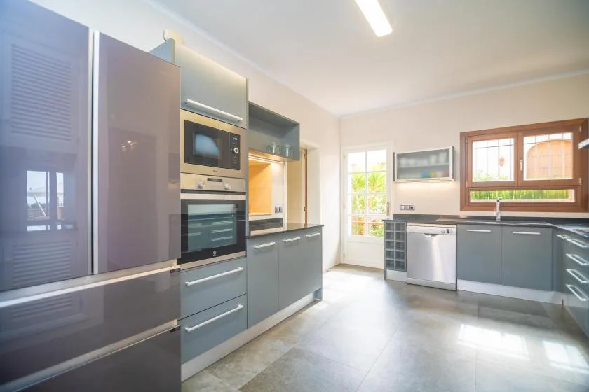 A bright kitchen with gray cabinets, built-in appliances, and a sink.
