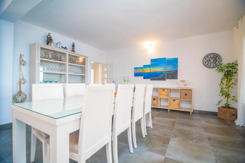 A bright dining room with a long white table and colorful wall art.
