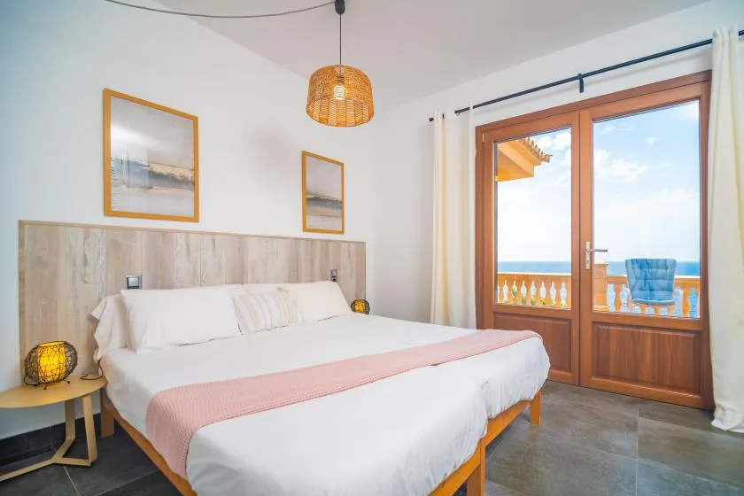 A bedroom with a double bed and glass doors opening onto a balcony.