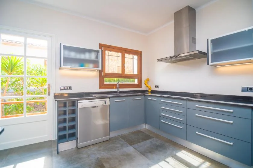 A modern kitchen with blue-gray cabinets and a stainless-steel range hood.