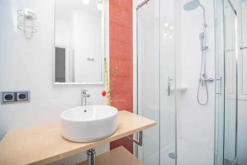 A bright bathroom with a vessel sink and glass shower.