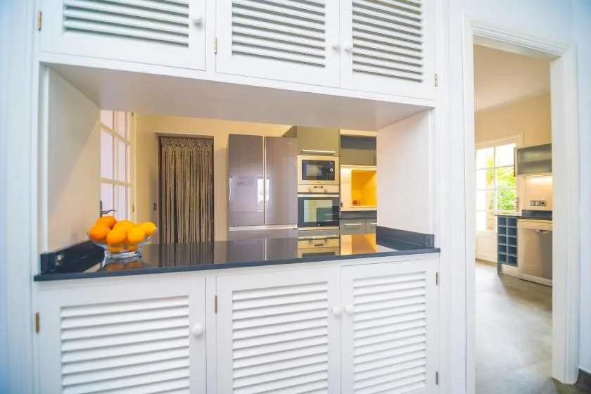 A bright kitchen with a pass-through counter and built-in appliances.