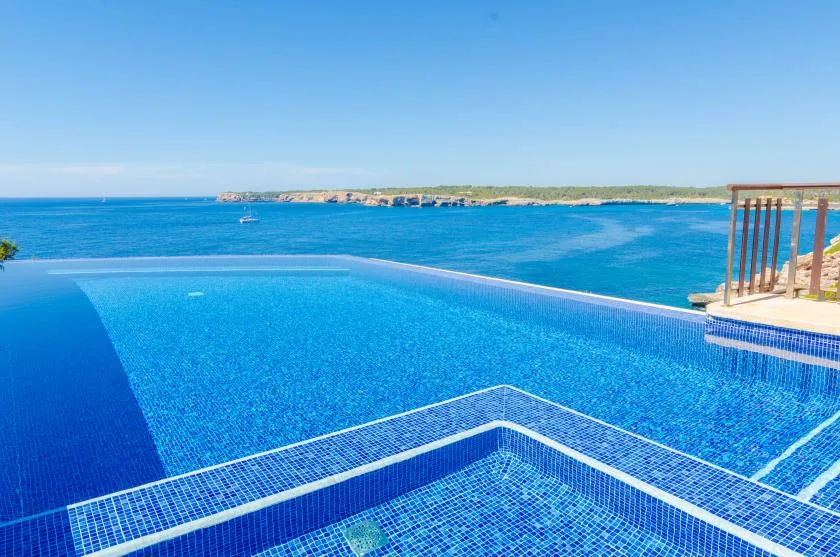 An infinity pool overlooks a blue bay and distant shoreline.