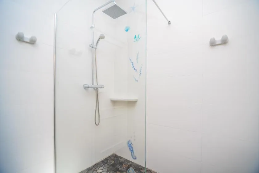 A bright shower area with a handheld showerhead and tiled walls.