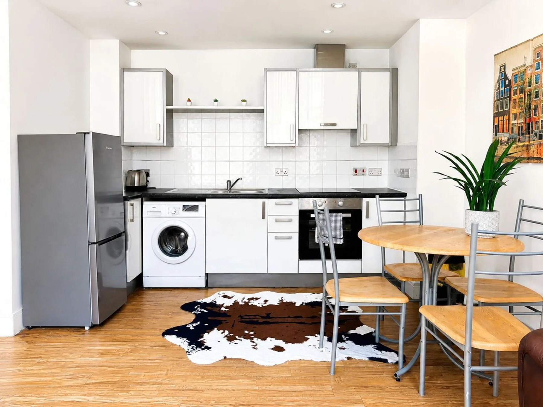 A bright kitchen and dining area with white cabinets and a wooden table.