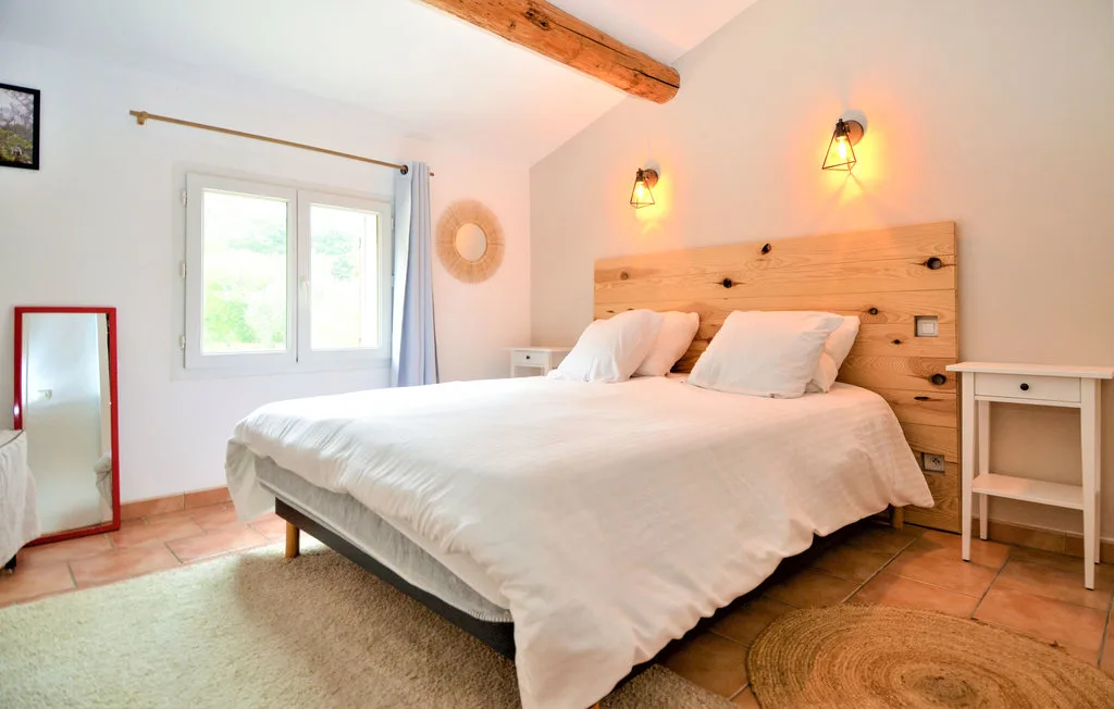 A bright bedroom with a large bed and wooden headboard.