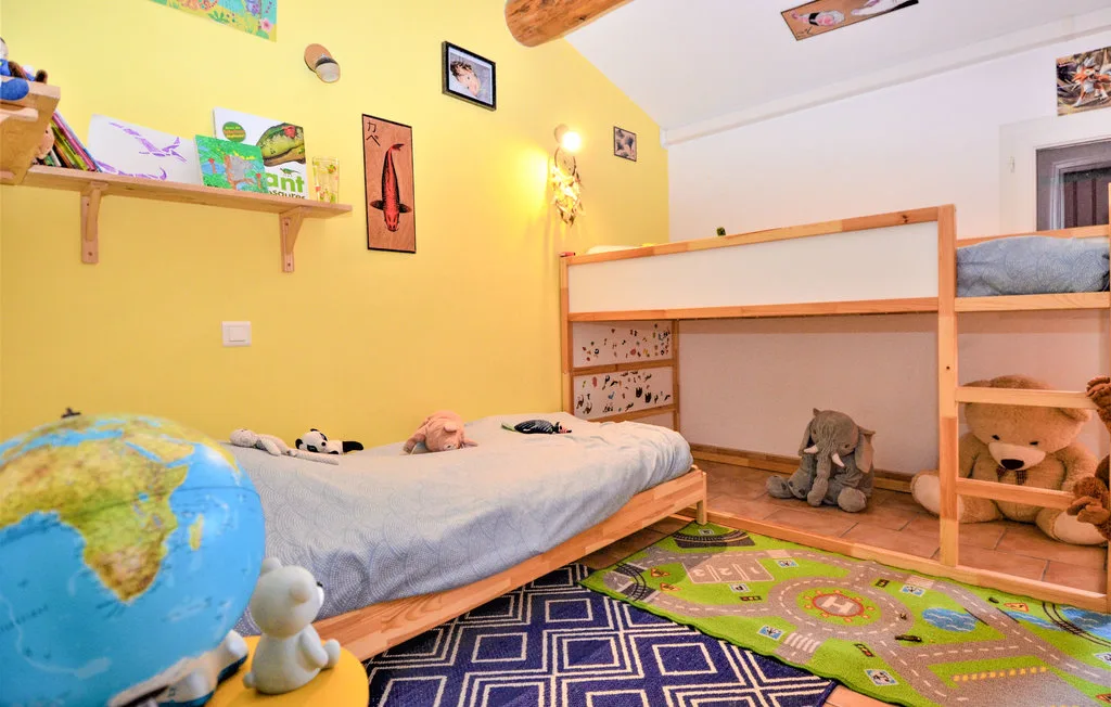 Un dormitorio infantil colorido con camas, juguetes y una alfombra estampada.