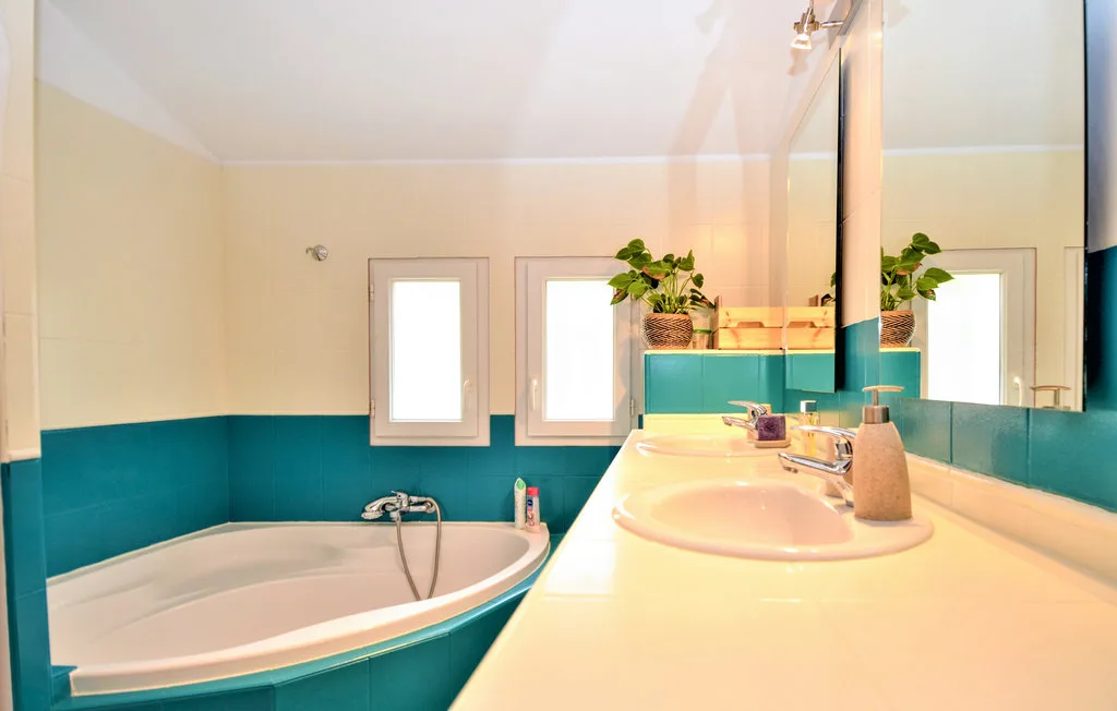 Un baño con bañera, lavabo y azulejos turquesa en las paredes.