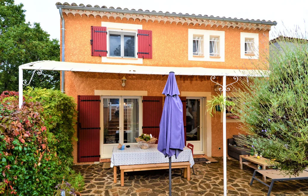Una casa naranja da a un patio de piedra con asientos al aire libre.