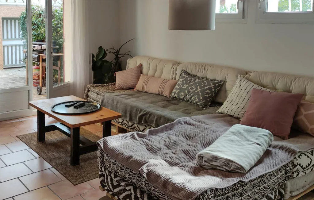 A living room with cushioned seating, a low table, and a large ottoman.