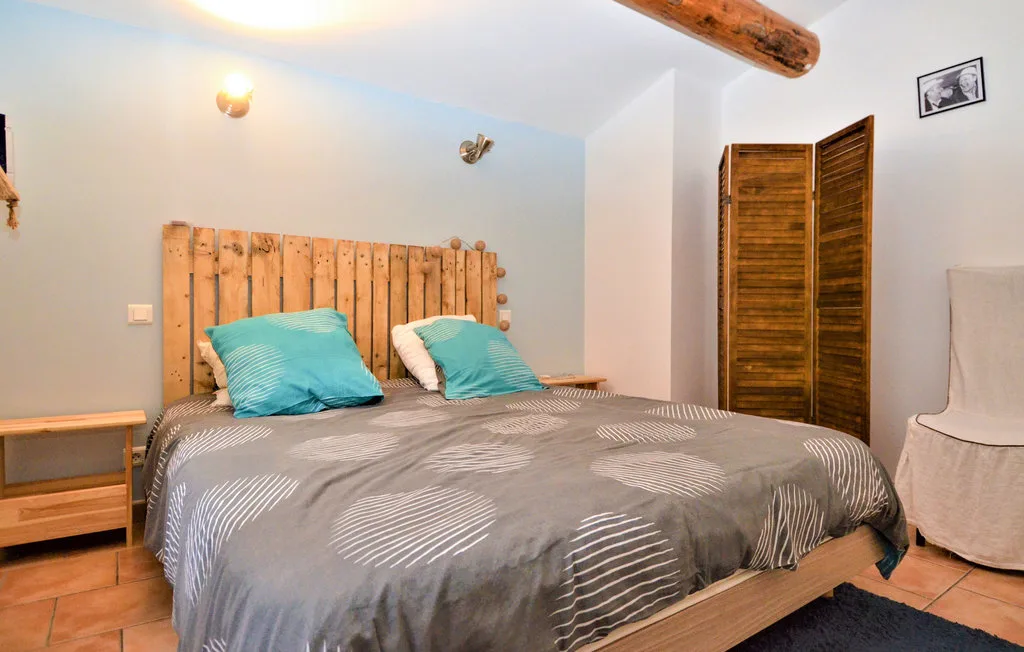 Un dormitorio con una cama de madera, ropa de cama estampada y almohadas turquesas.