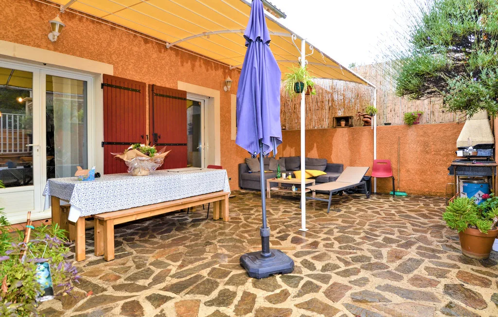 An outdoor patio with a dining table, seating, and a closed umbrella.