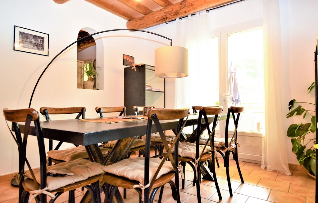 Un comedor con una mesa larga, sillas y una lámpara colgante grande.