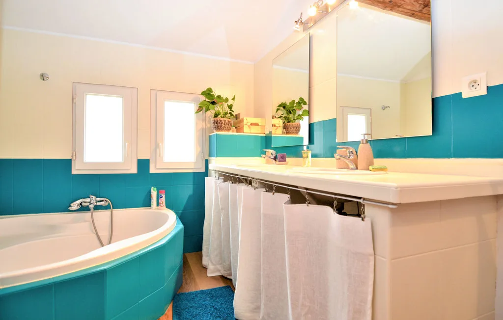 Un baño luminoso con bañera, tocador y azulejos turquesa.