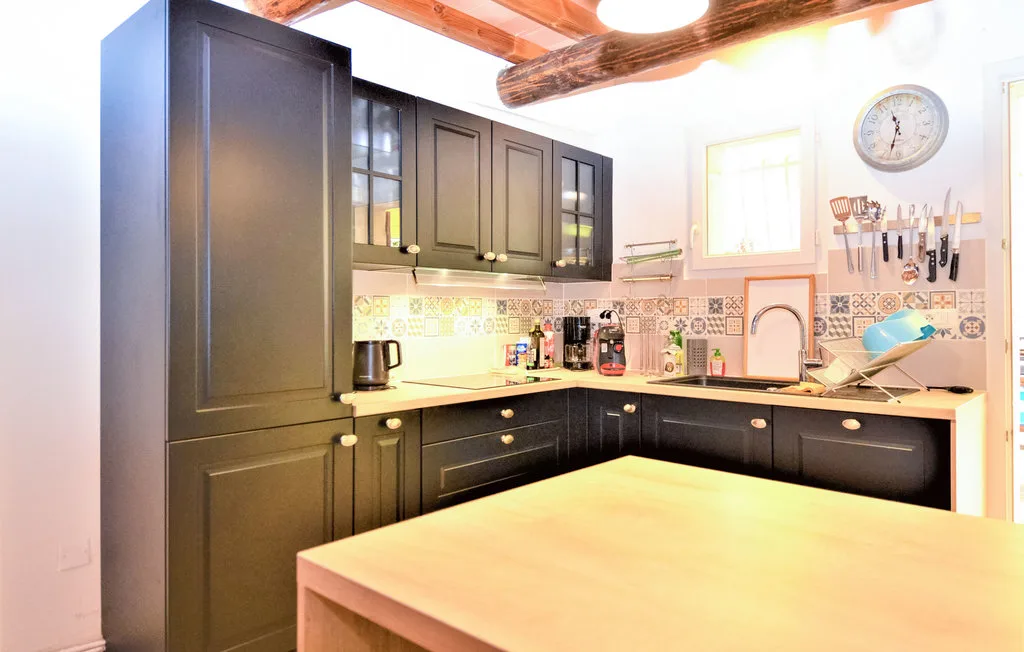 Una cocina con gabinetes oscuros, un fregadero y una gran isla de madera.