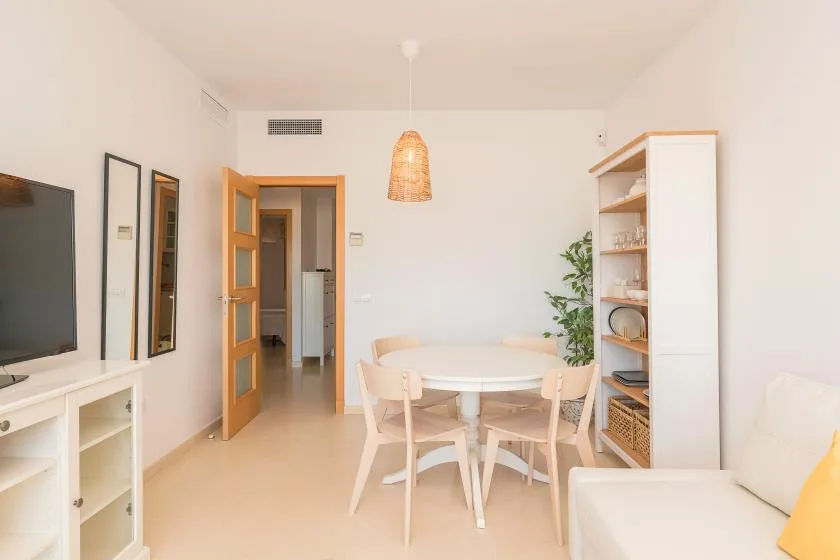 A bright dining and living area with a round table, seating, and open shelving.