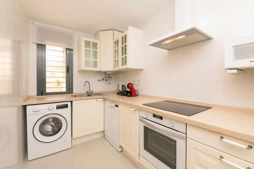 A bright kitchen with a washing machine, cooktop, and built-in oven.