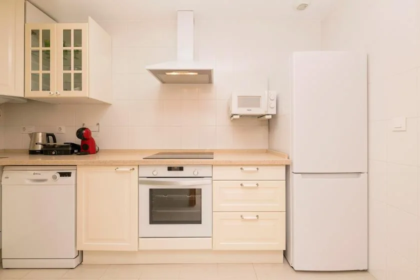 A bright kitchen with light cabinetry, an oven, and a refrigerator.