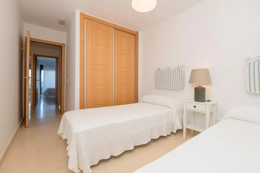 A bright bedroom with two beds and wooden wardrobes.