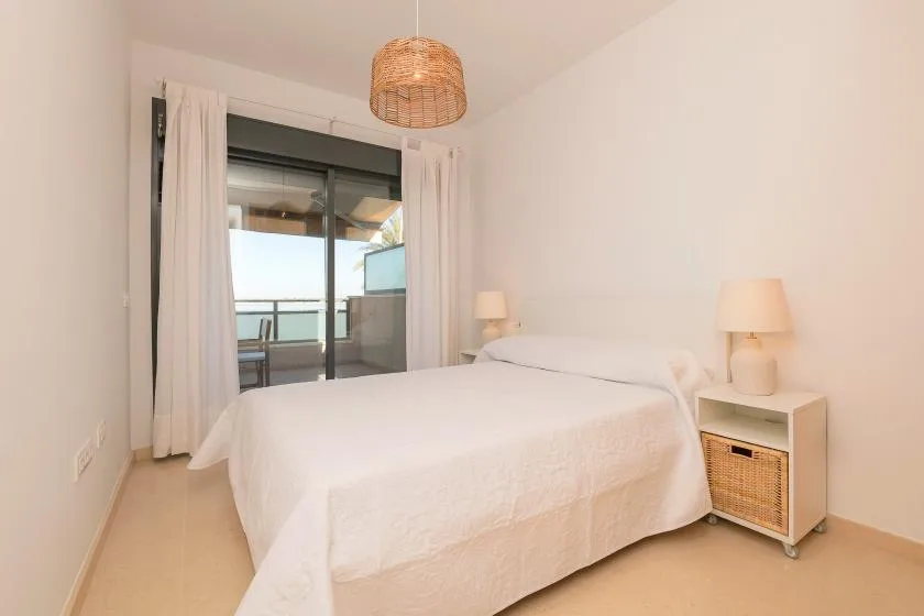 A bright bedroom with a neatly made bed and sliding glass doors.