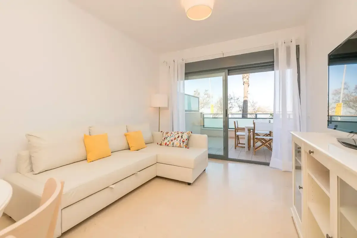 A bright living room with a sectional sofa and a dining table by the glass doors.