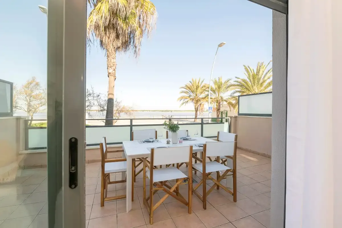 A tiled outdoor dining area has a table and chairs beside the glass doors.