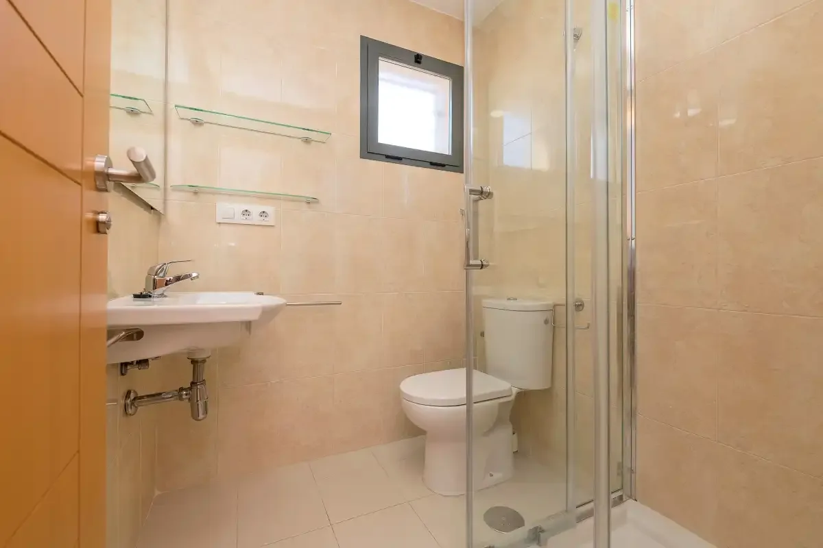 A bathroom with a sink, toilet, and glass shower.